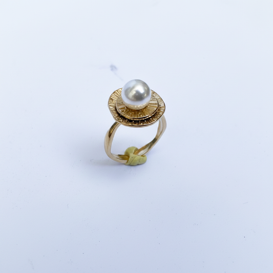 Bague dorée perle blanche dessus fond blanc
