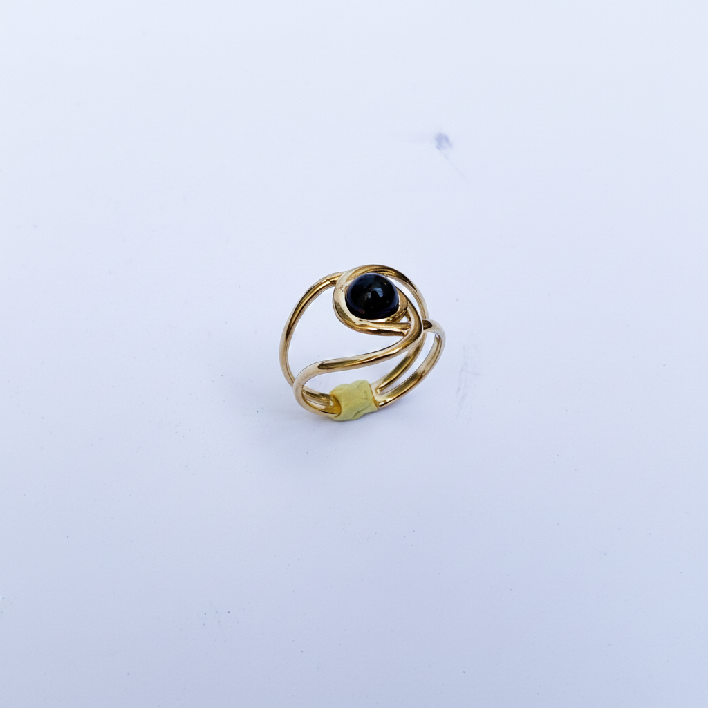 Bague dorée double anneau pierre noire dessus fond blanc