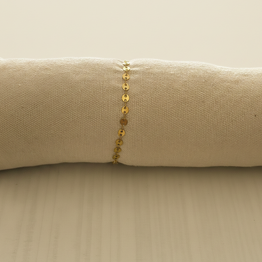 Bracelet sequins dorés sur coussin fond beige