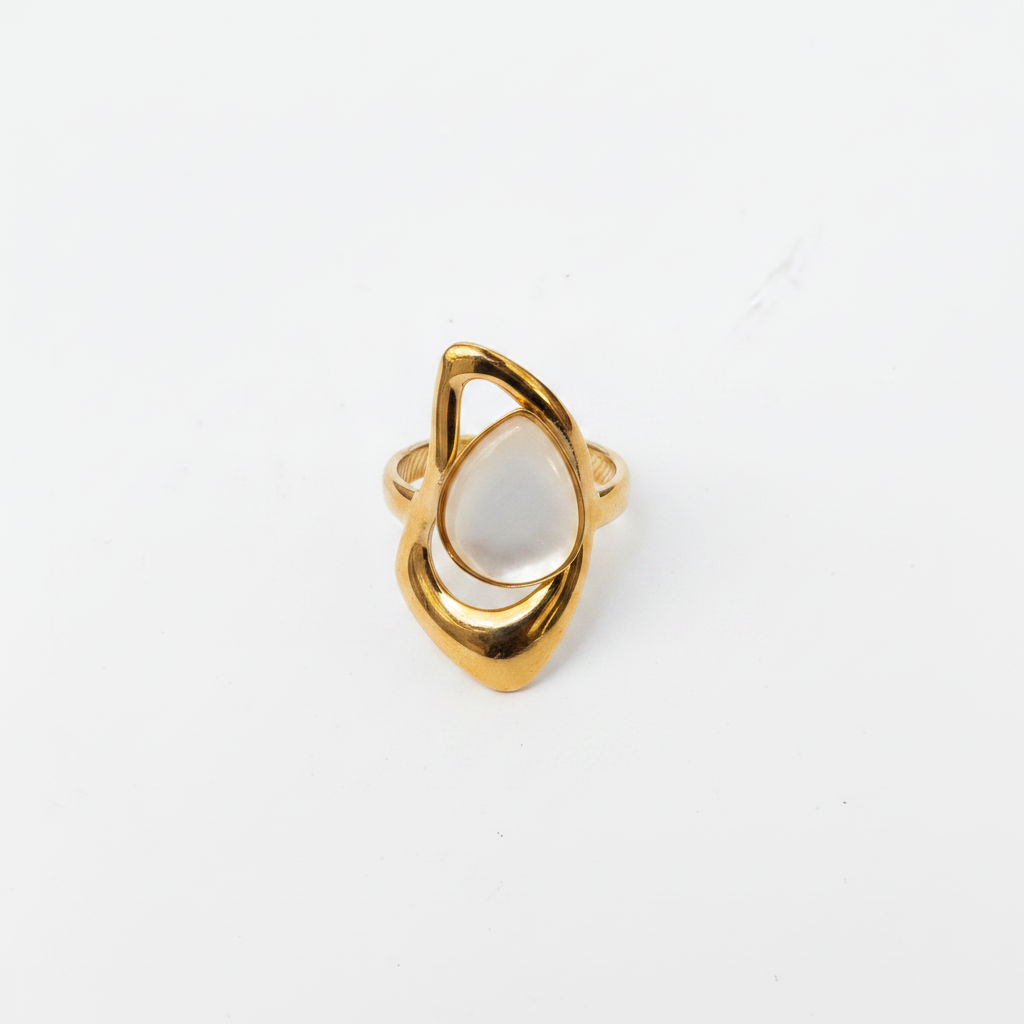Bague dorée nacre goutte dessus fond blanc