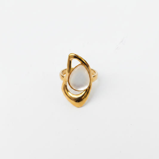 Bague dorée nacre goutte dessus fond blanc