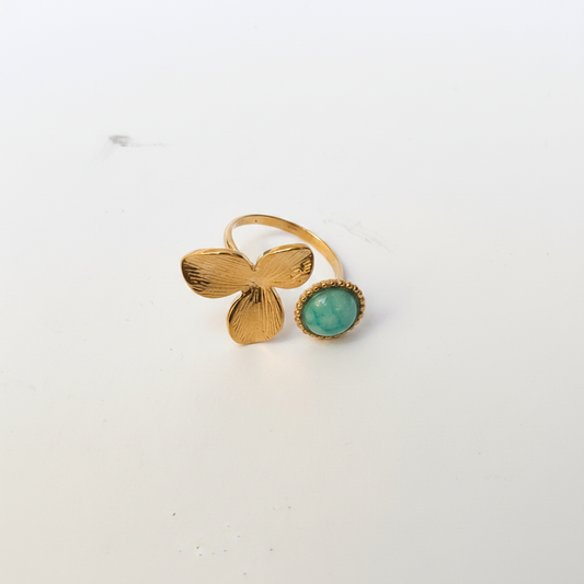 Bague fleur dorée turquoise dessus fond blanc